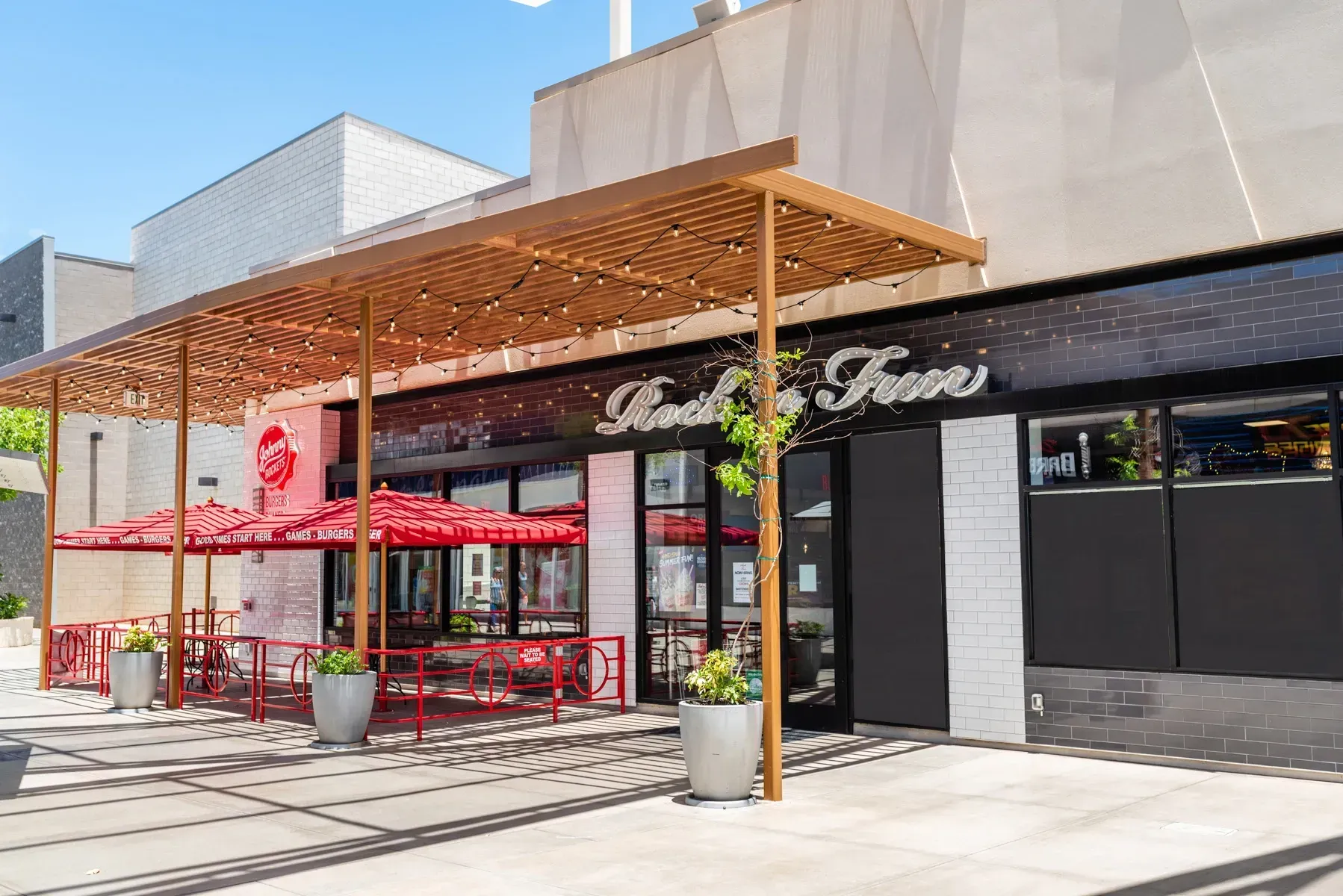 A restaurant with umbrellas and potted plants in front of it.