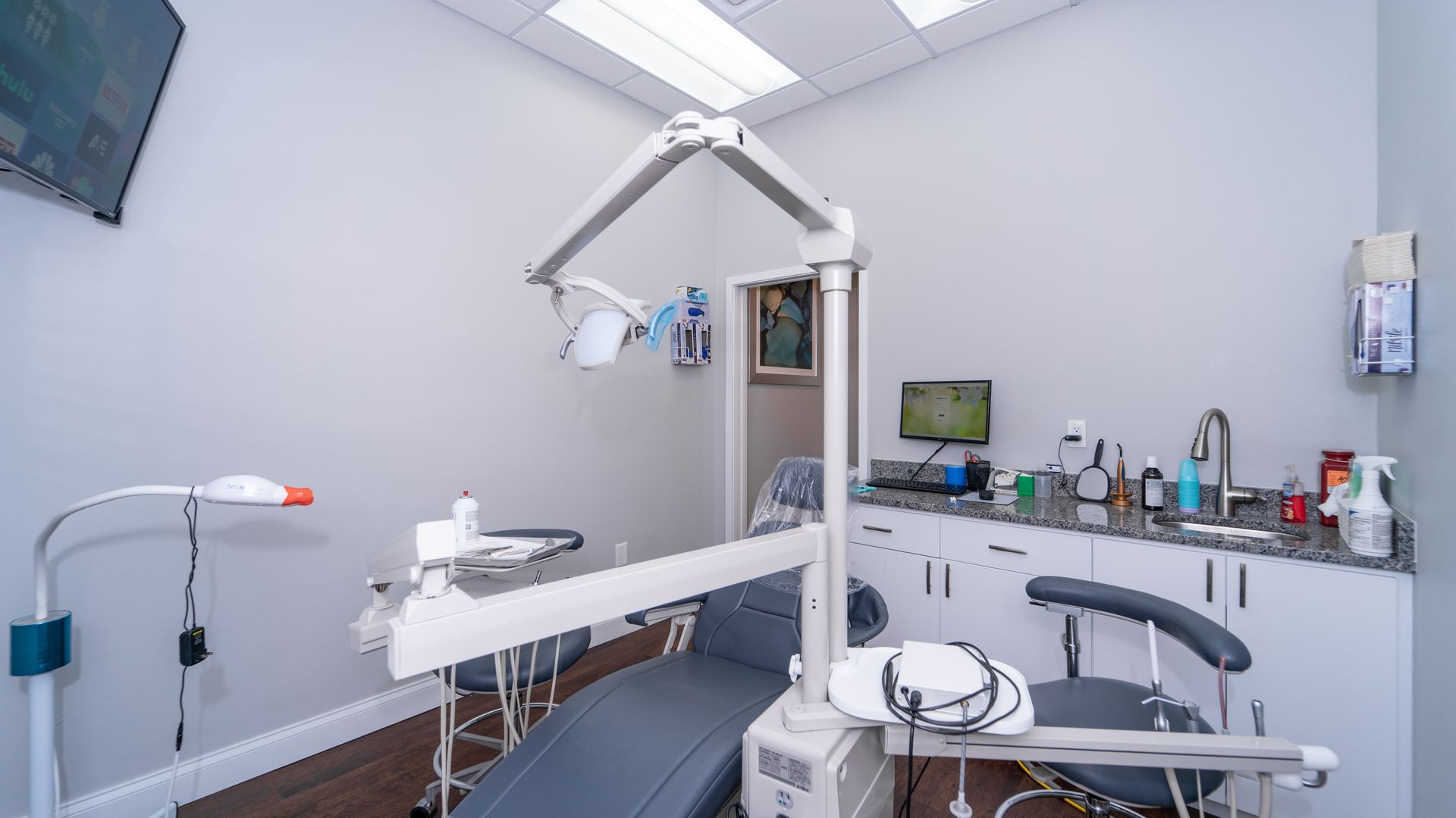 A dental office with a dental chair and a sink.