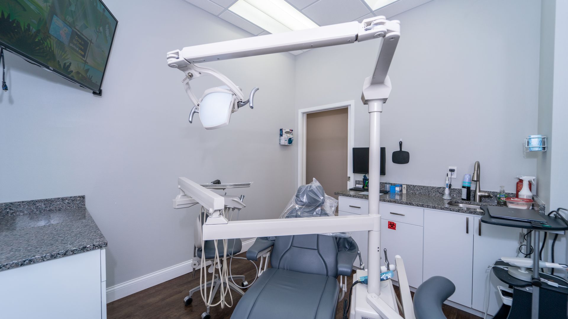 A dental office with a dental chair and a television on the wall.