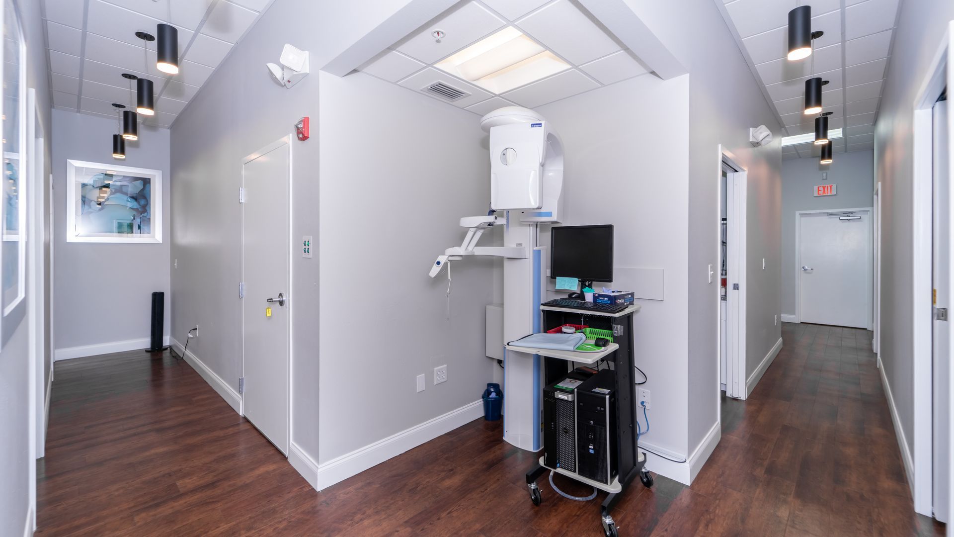 A hallway in a dental office with a computer on a cart.