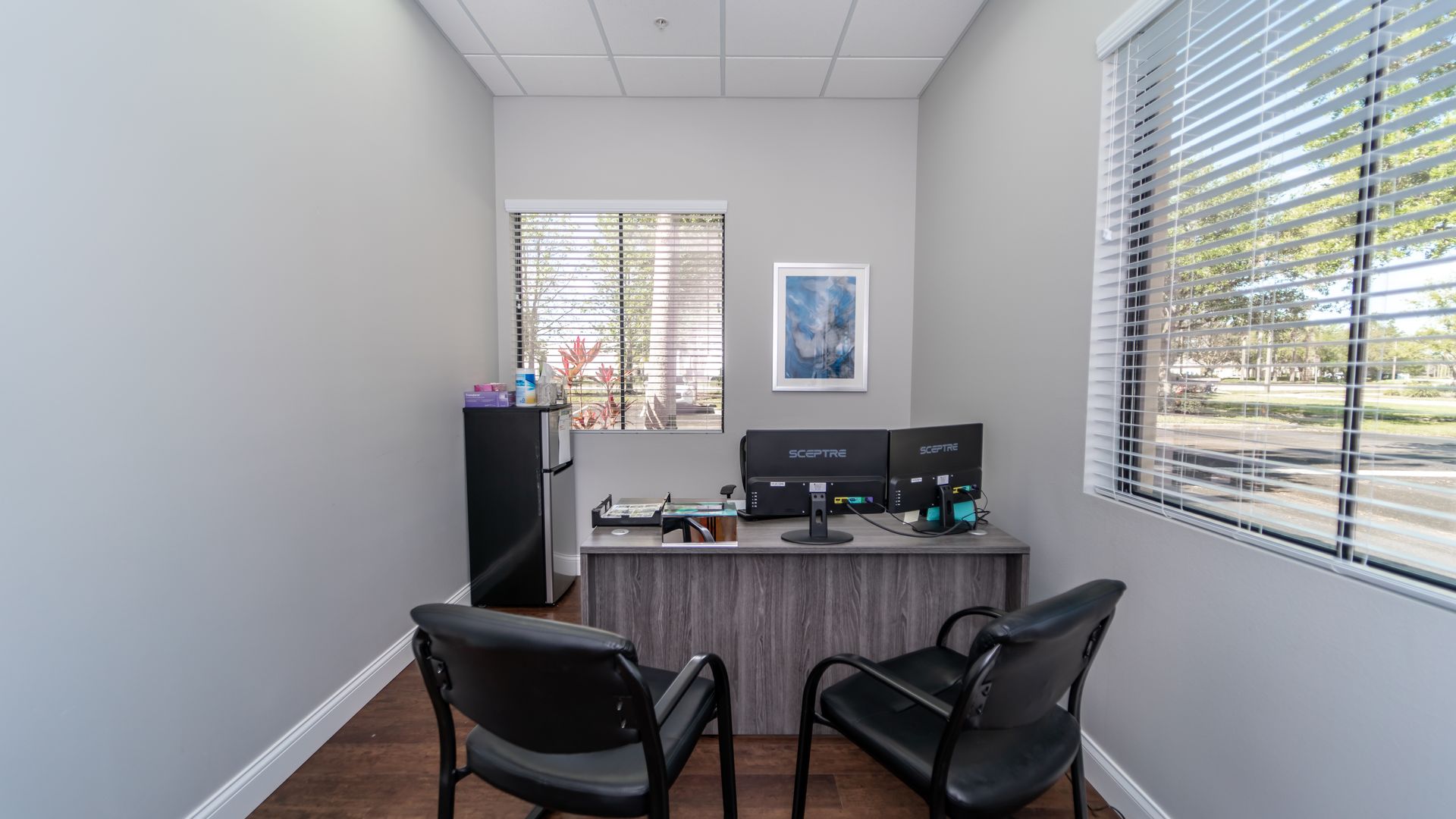 A small office with two chairs , a desk , and a window.
