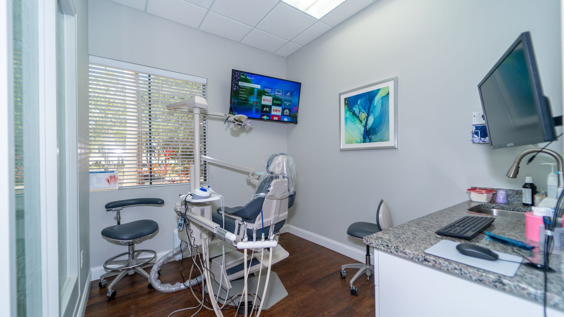 A dental office with a dental chair and a television on the wall.