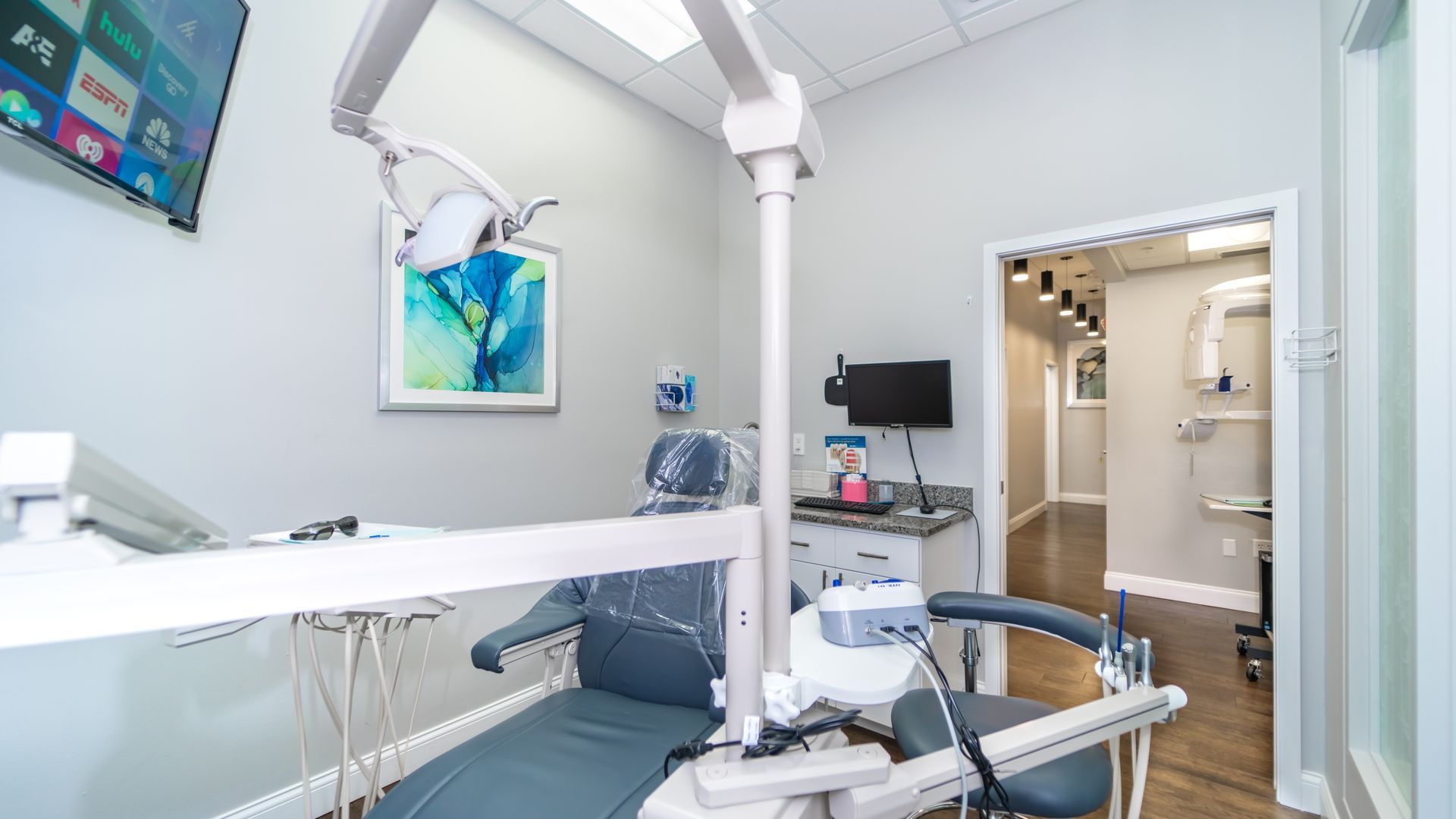 A dental office with a dental chair and a television on the wall.