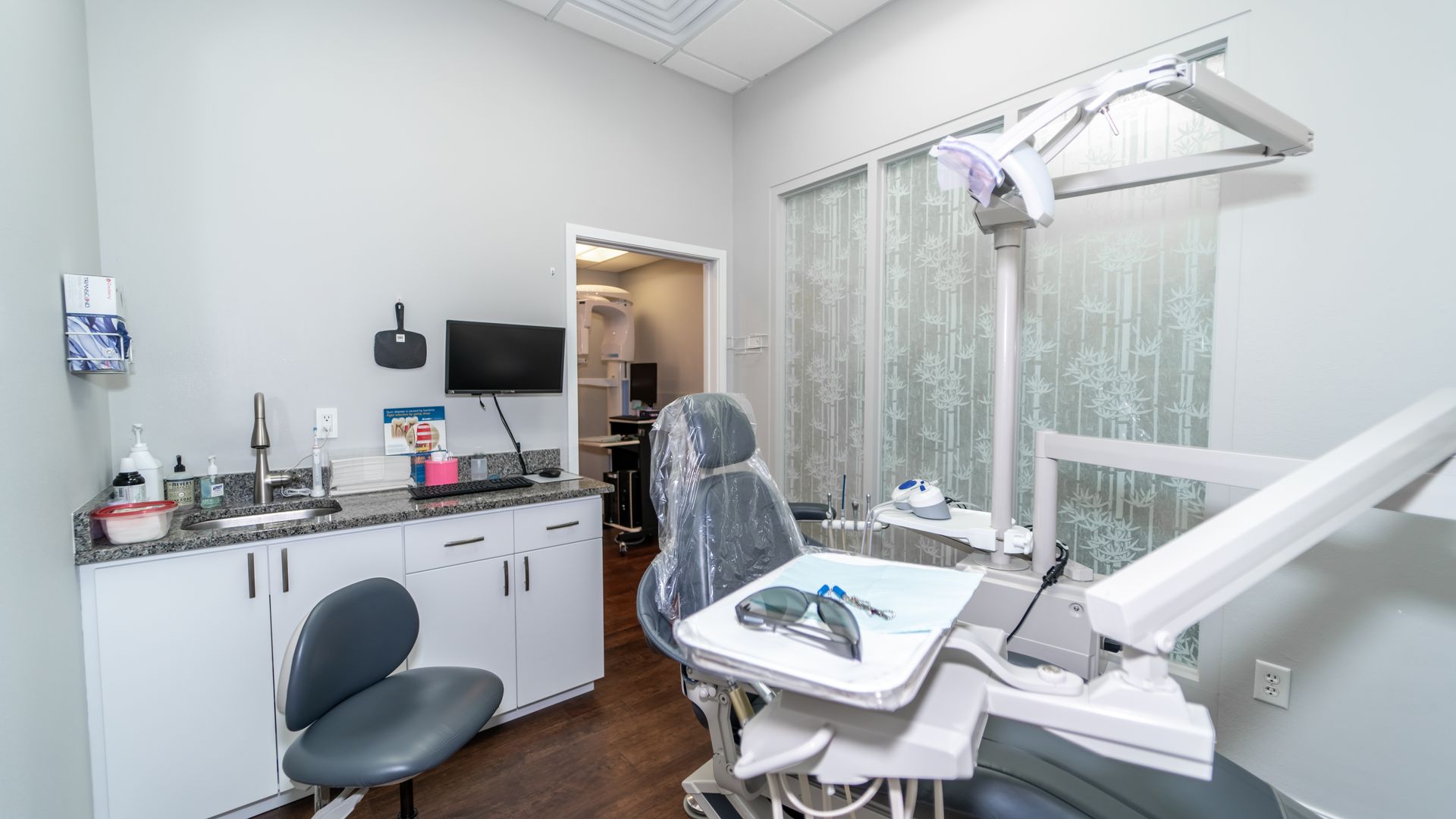 A dental office with a dental chair and a sink.