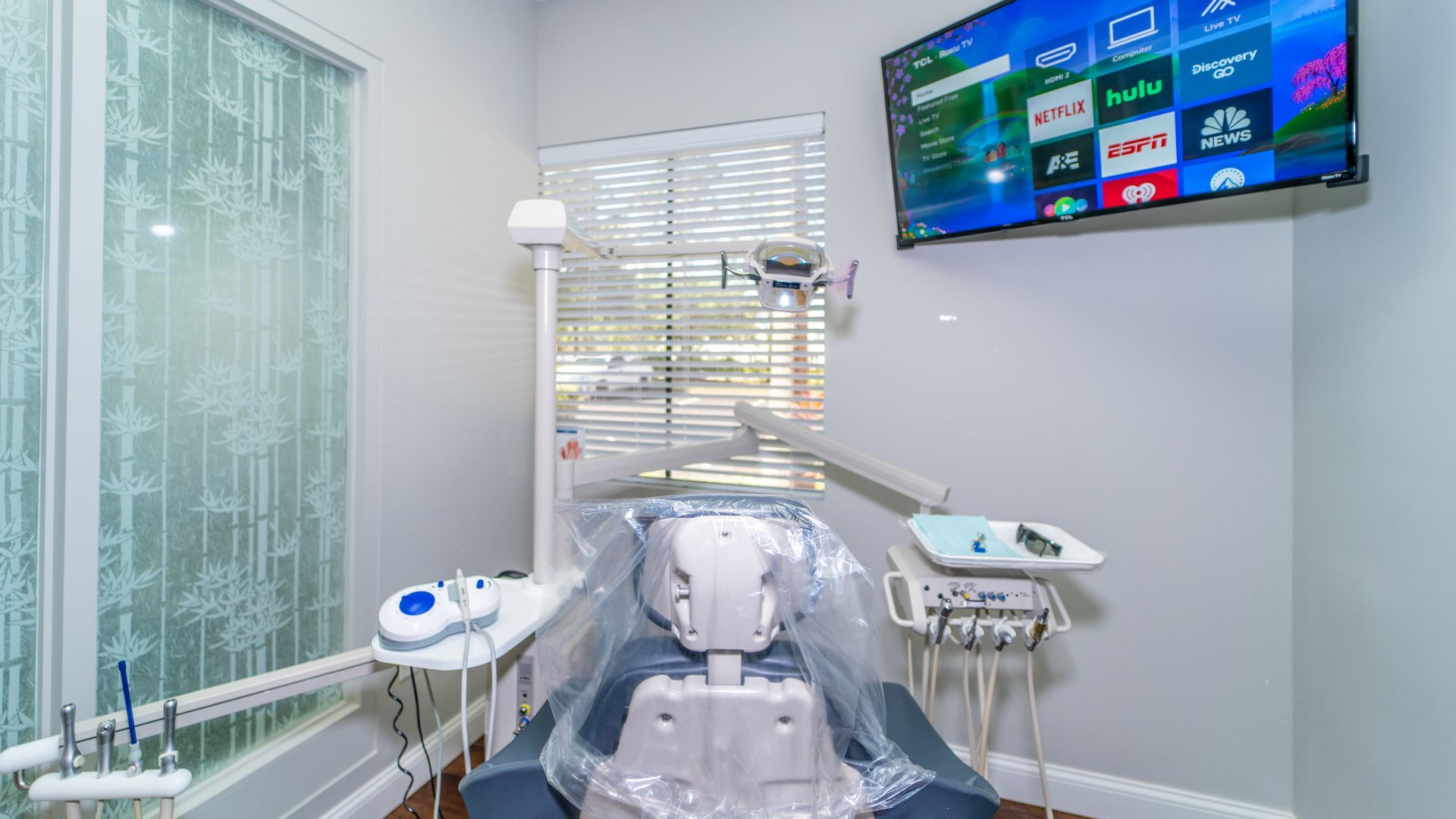 A dental office with a dental chair and a television on the wall.