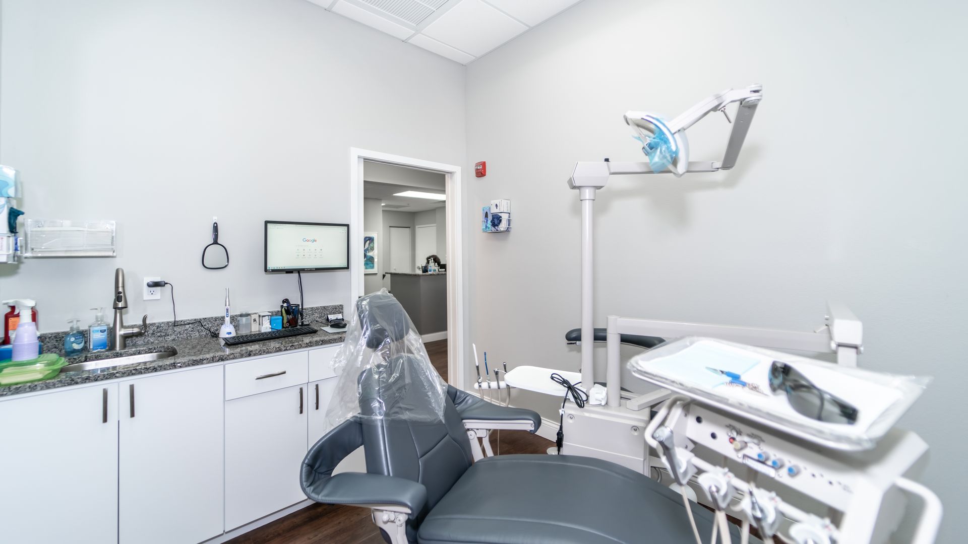 A dental office with a dental chair and a sink.