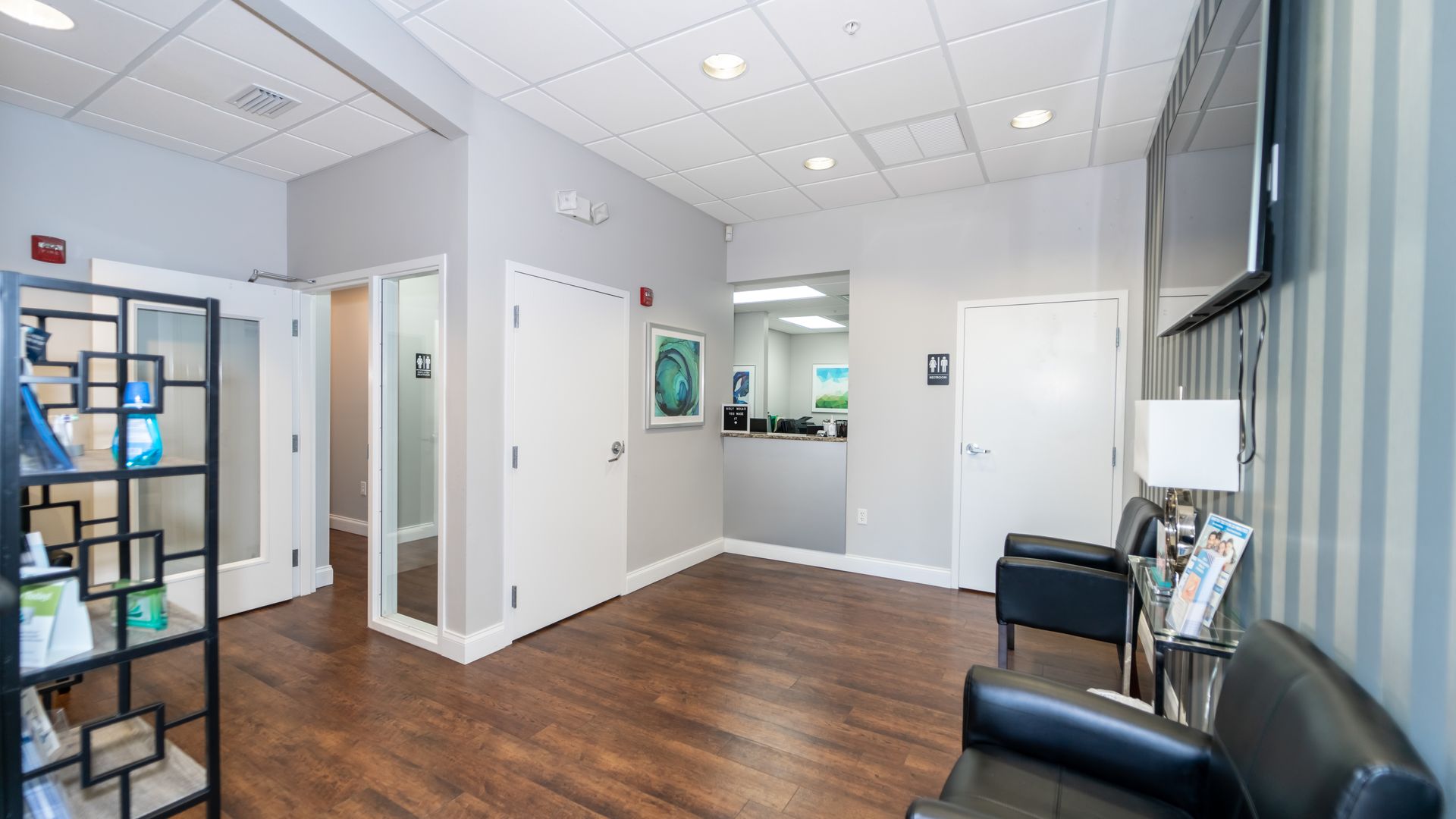 A waiting room with a couch and chairs in a dental office.