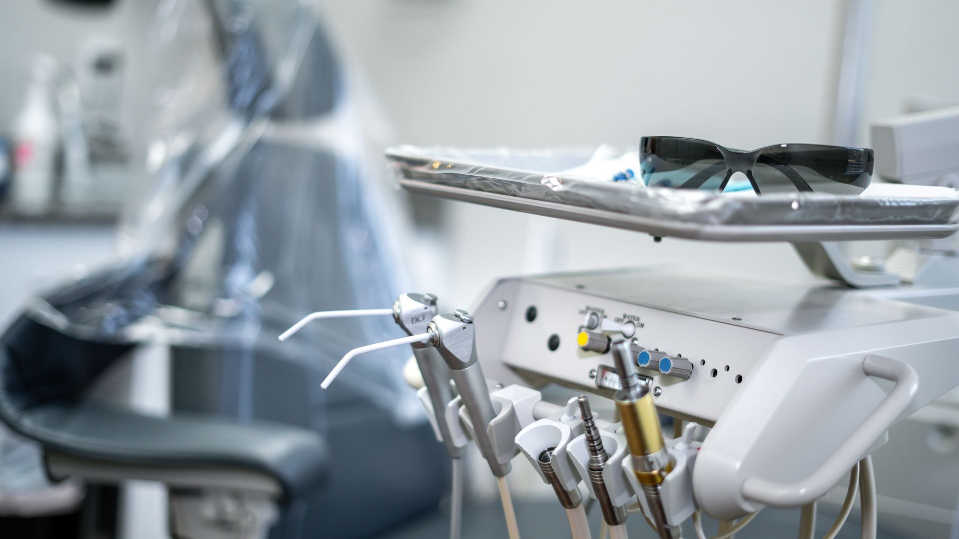 A dental chair with a tray of dental instruments on it in a dental office.