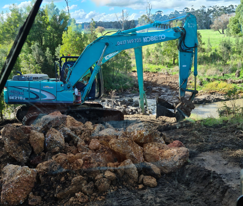A yellow excavator is digging a hole in the ground.