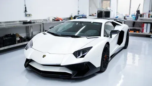 A white lamborghini aventador is parked in a garage.