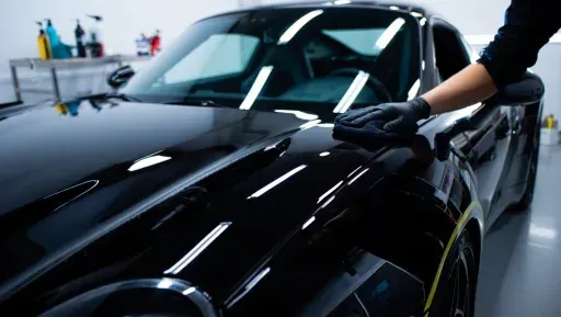 A person is polishing a black car in a garage.