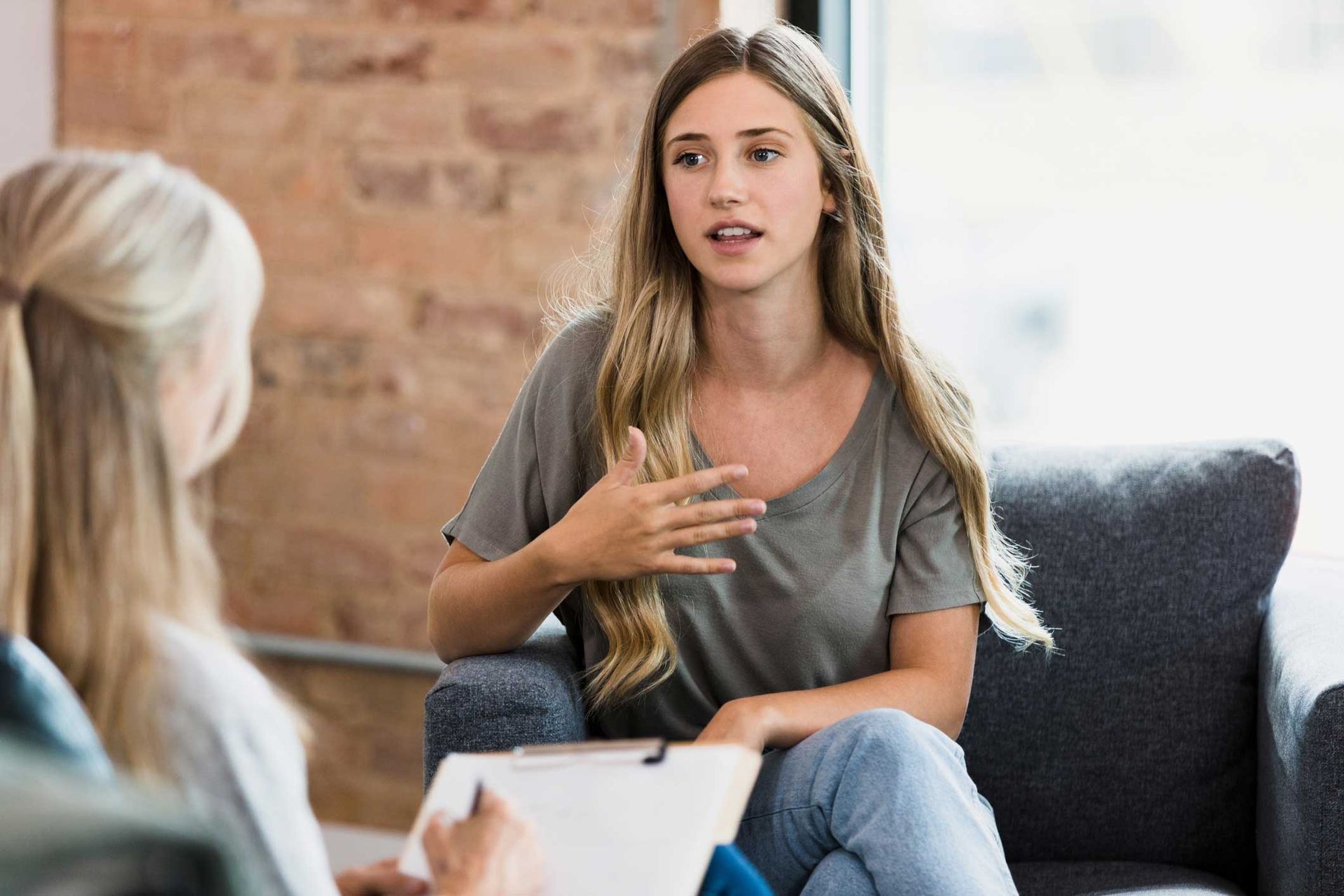 A woman is sitting in a chair talking to another woman.