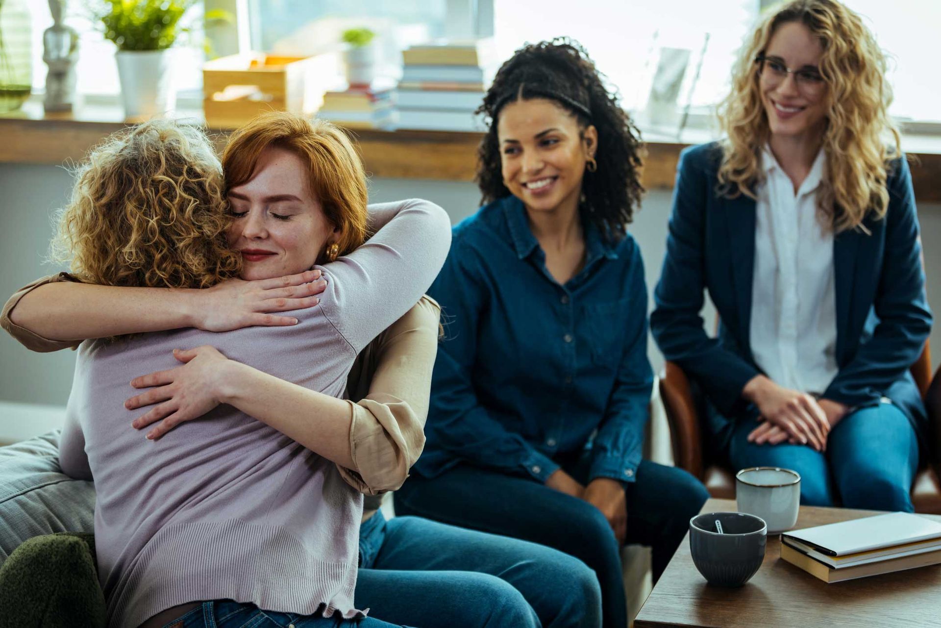 A group of women are hugging each other while sitting on a couch.