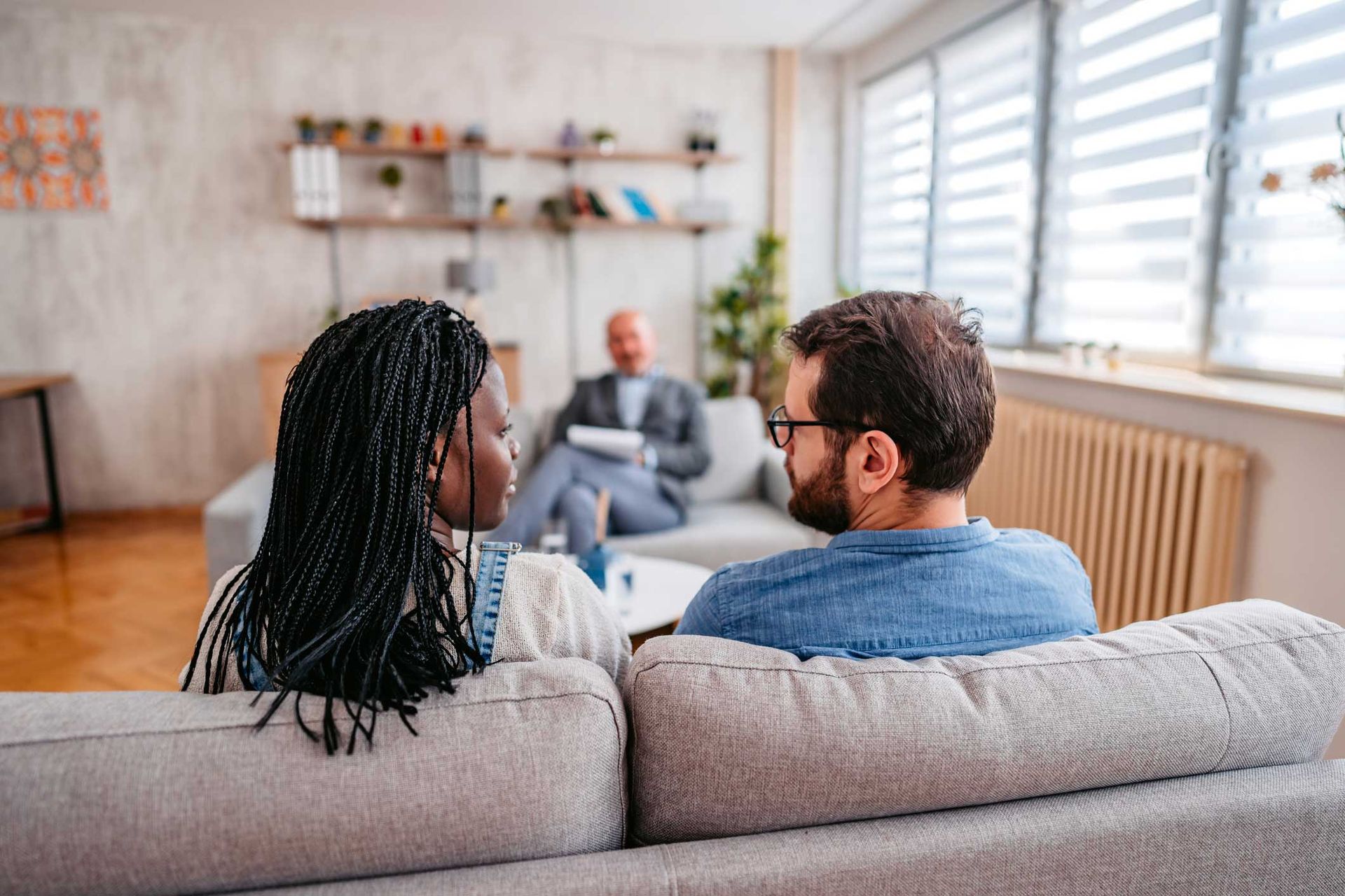 A man and a woman are sitting on a couch talking to each other.