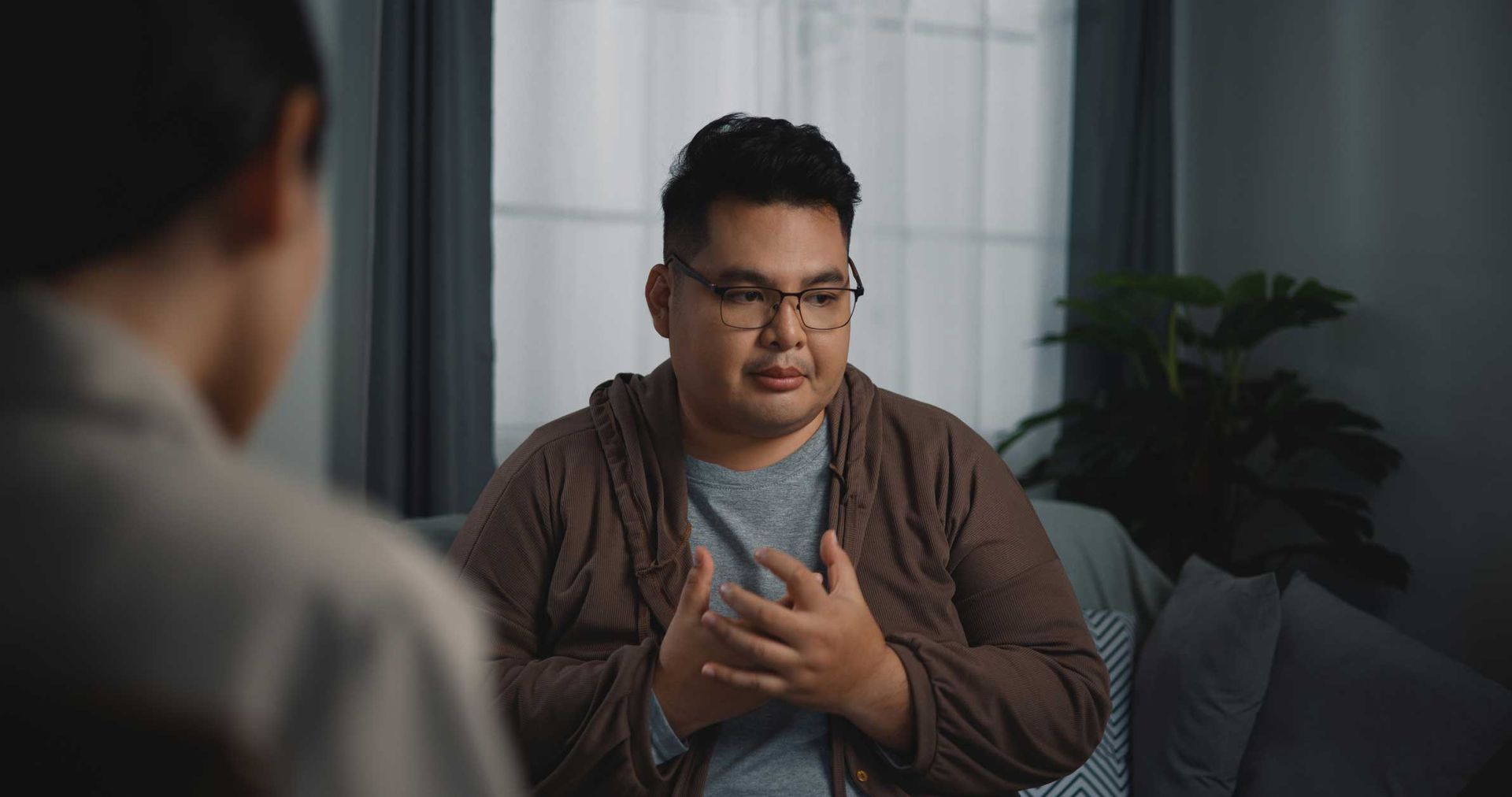 A man is sitting on a couch talking to another man.