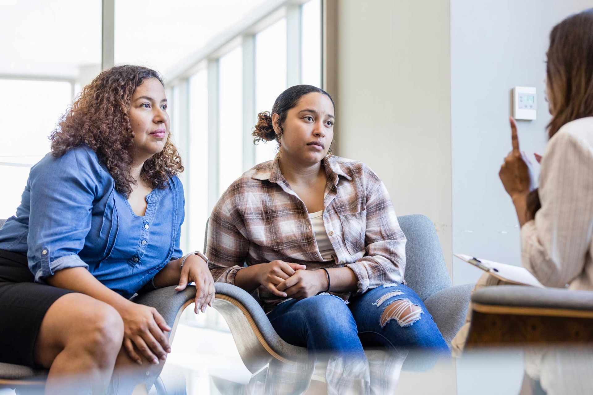 Two women are sitting on a couch talking to a woman.