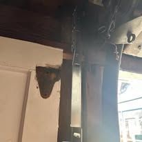 Wooden post with metal hardware, likely a door hinge or support, in an old building.