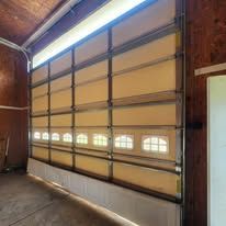 Garage door with multiple frosted glass panels, some open, in a dimly lit space.