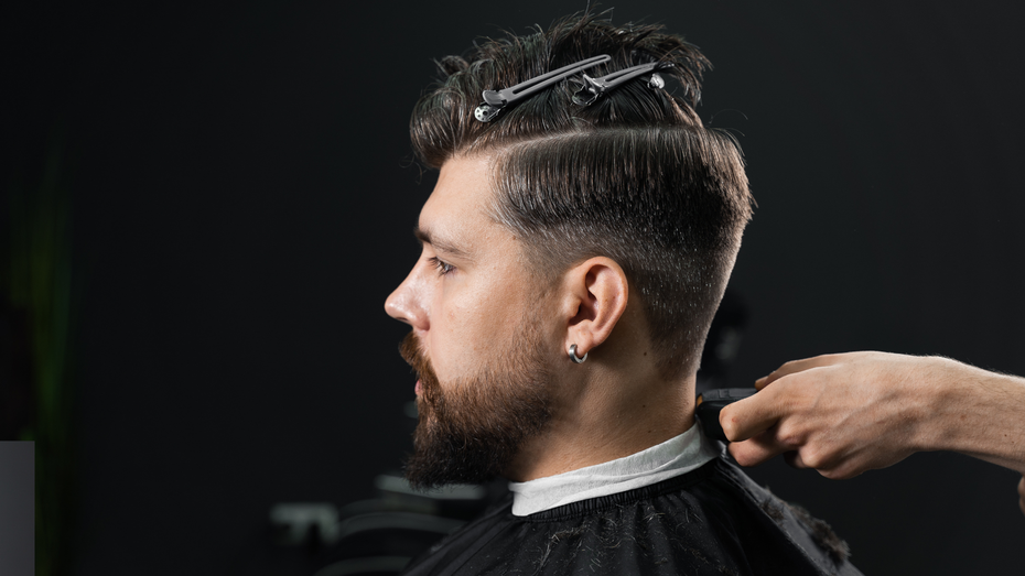 A man is getting his hair cut by a barber in a barber shop.