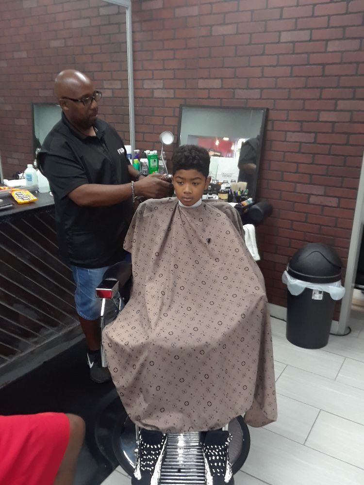 A boy is getting his hair cut at a barber shop