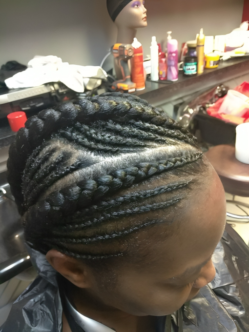 A woman is getting her hair braided in a salon