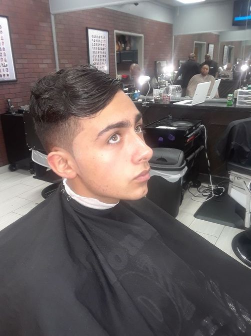 A young man is getting his hair cut at a barber shop.