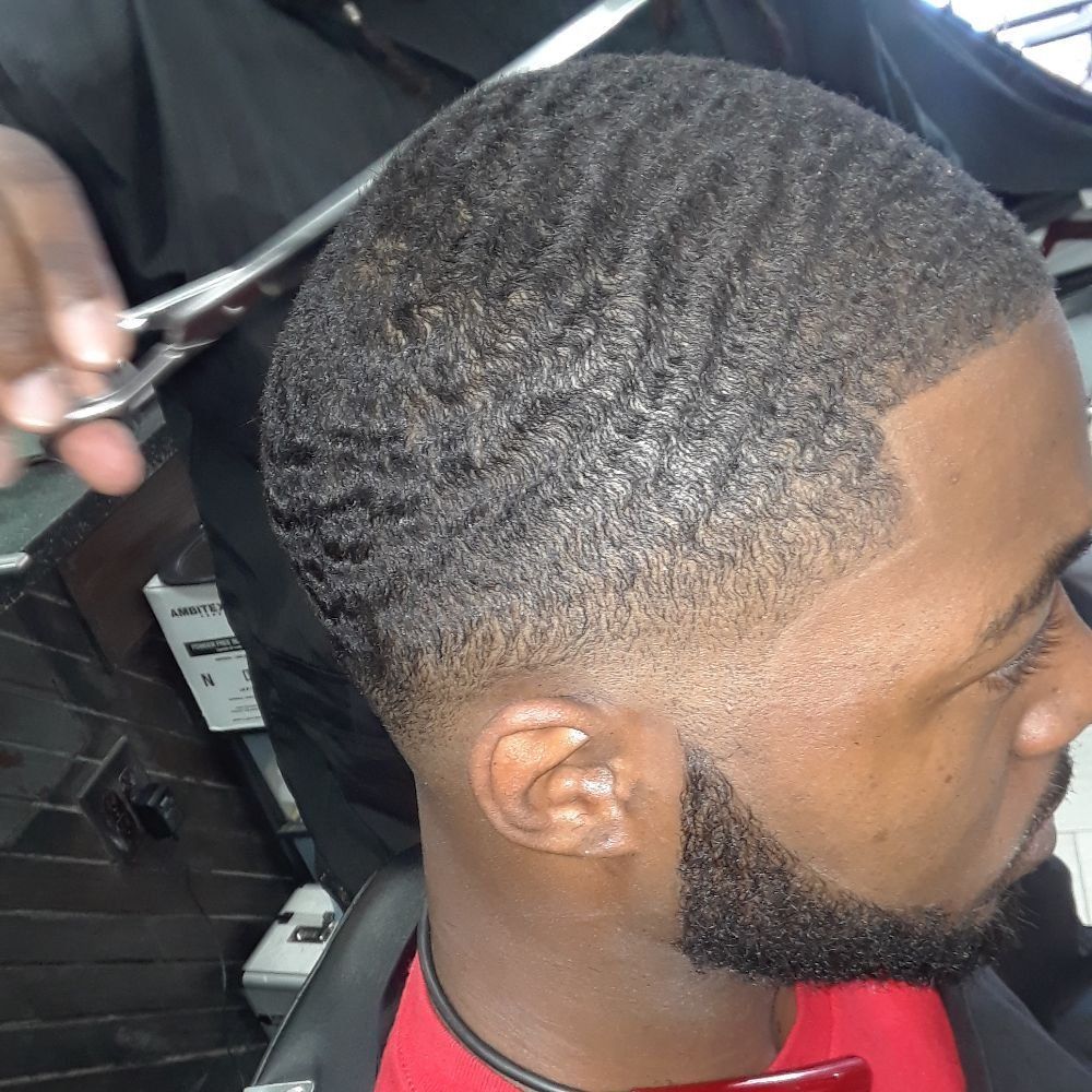 A man with a beard is getting his hair cut by a barber