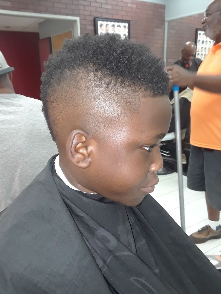 A young boy is getting his hair cut at a barber shop