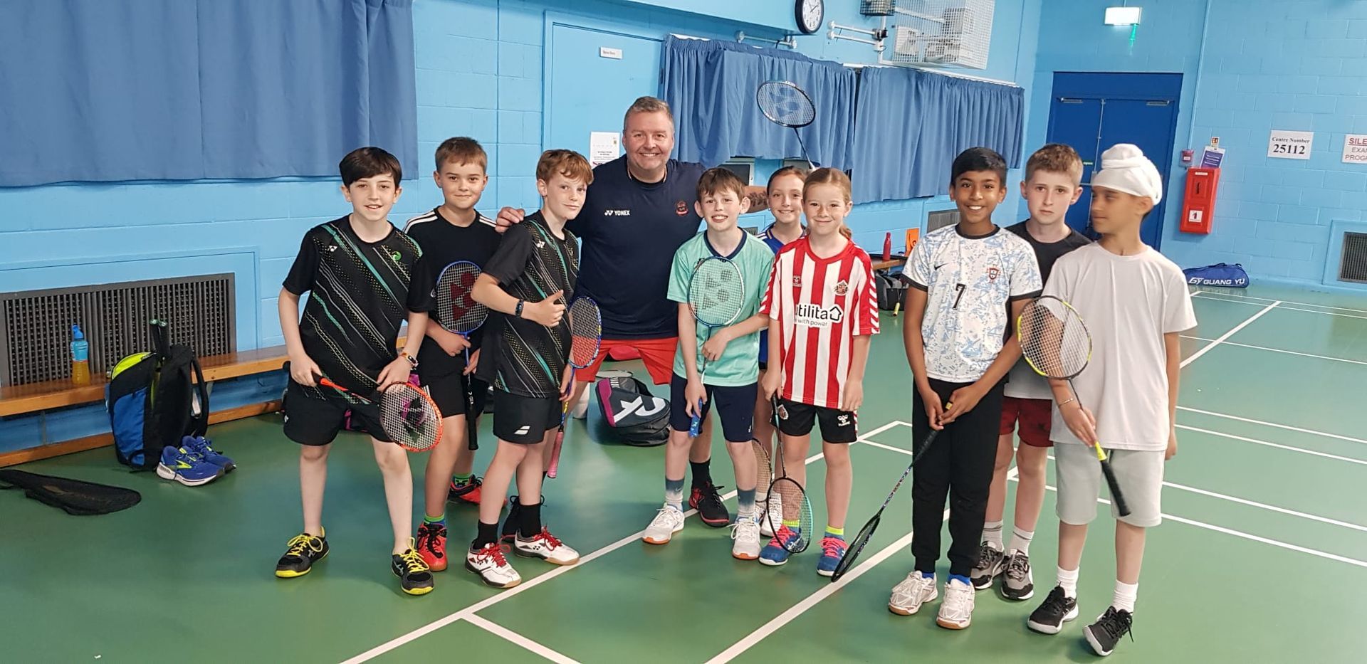 A group of young boys are posing for a picture on a badminton court.