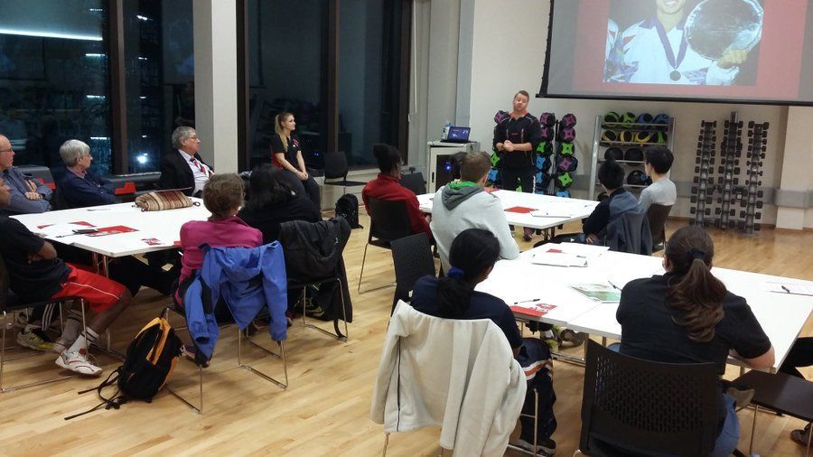 A group of people are sitting at tables in front of a projector screen