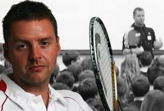 A man is holding a tennis racquet in front of a crowd of people