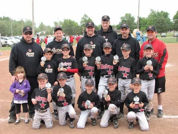 Youth baseball team posing for a group photo on a field, wearing black and red uniforms.
