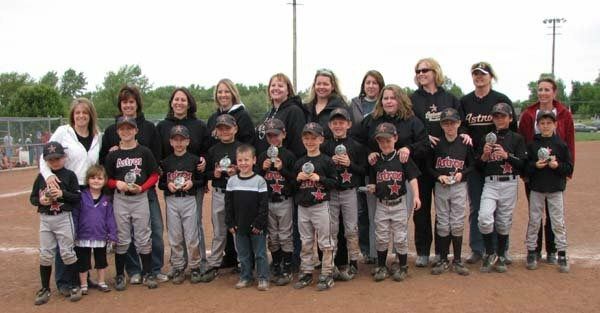 Youth baseball team and coaches posing together on a dirt field, wearing matching black jerseys.