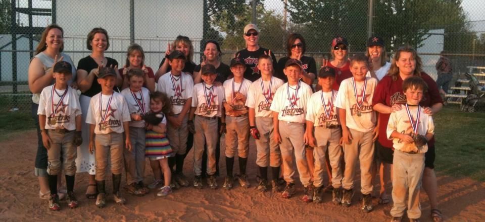 Youth baseball team and coaches posing outdoors at sunset in front of a building