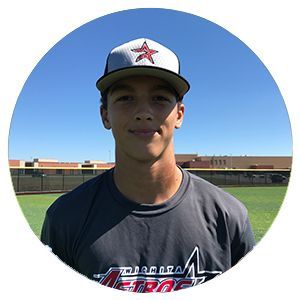 Baseball player in a dark shirt and cap standing on a field under a blue sky