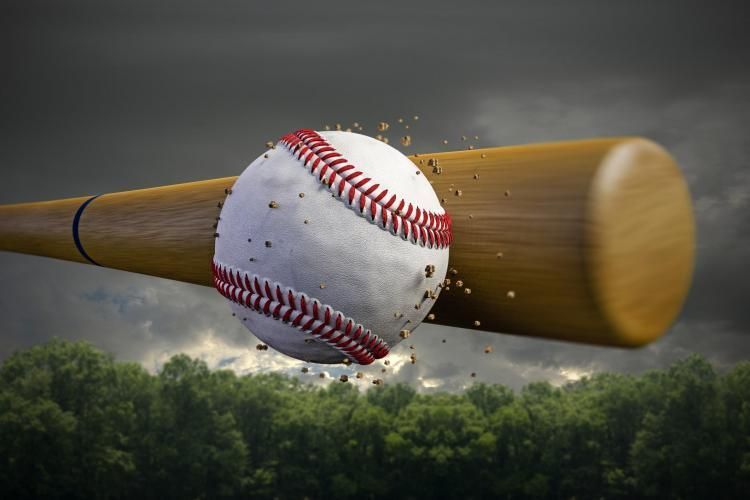 Baseball bat smashing a baseball in flight over a dark cloudy sky and treeline