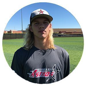 Young baseball player in an Astros shirt and cap standing on a field under a blue sky