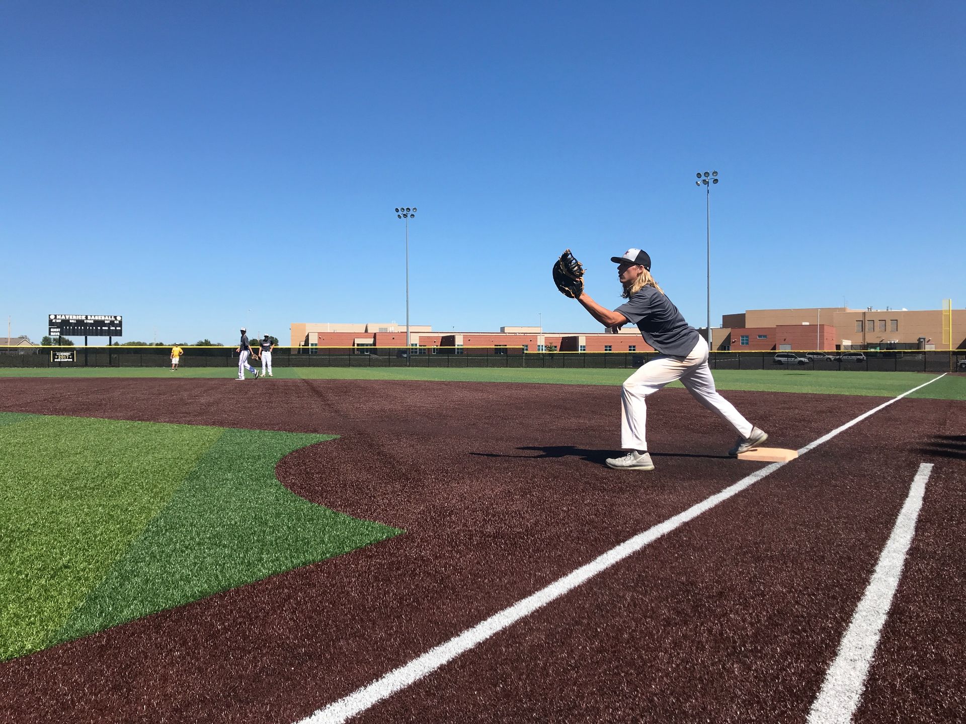Baseball player in gray uniform catching a ball on the field near the foul line.
