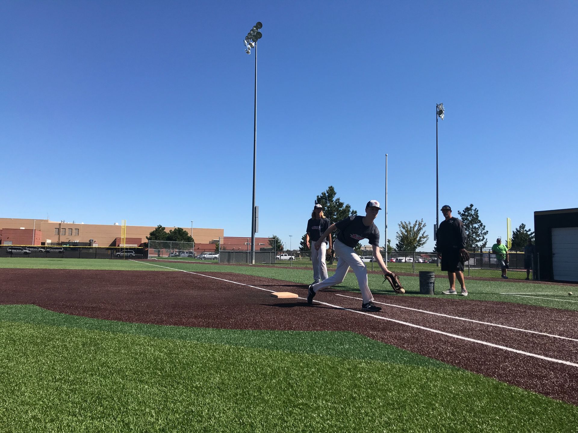 Baseball players on a field during practice under a clear blue sky