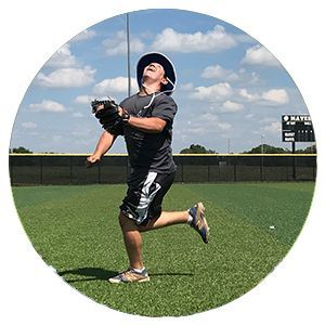 Baseball player in black uniform catching a ball on a sunny field