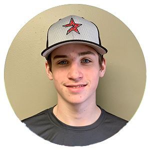Young person wearing a gray cap with a red star, smiling against a plain beige background