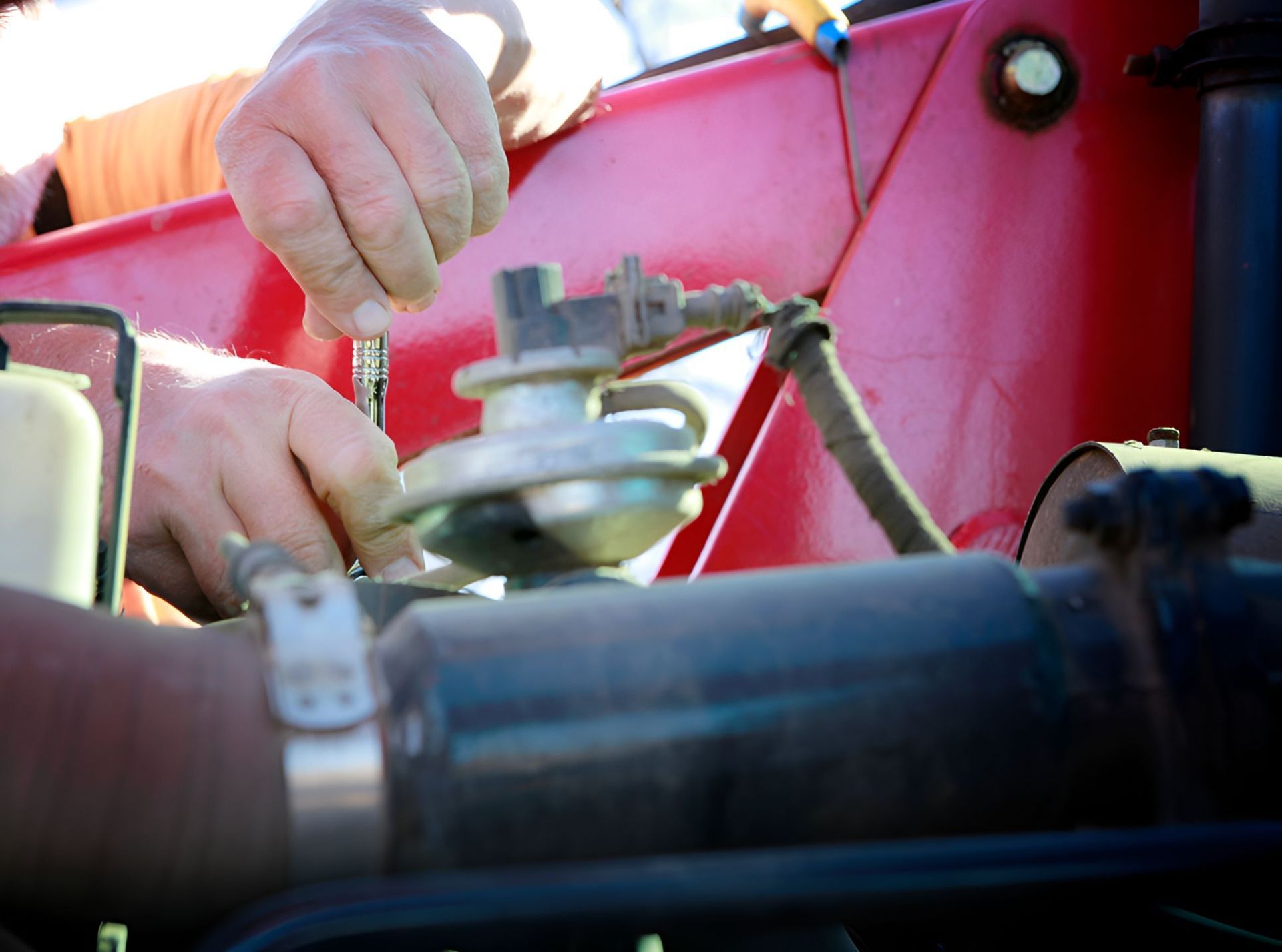 A Man is Working on a Red Vehicle With a Screwdriver — North Coast Construction Equipment In Grafton, NSW