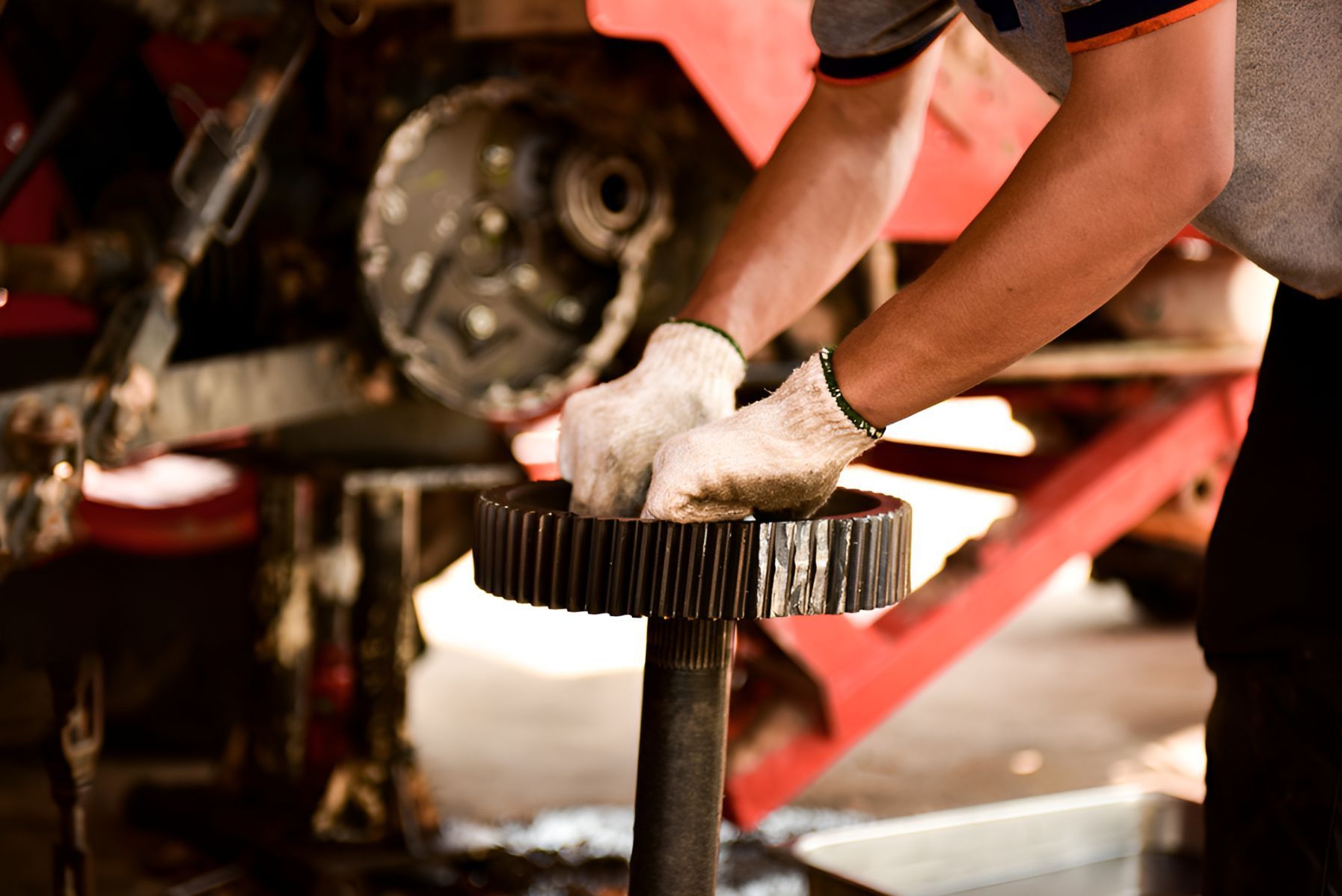 A Man is Working on a Gear in a Garage — North Coast Construction Equipment In Dorrigo, NSW
