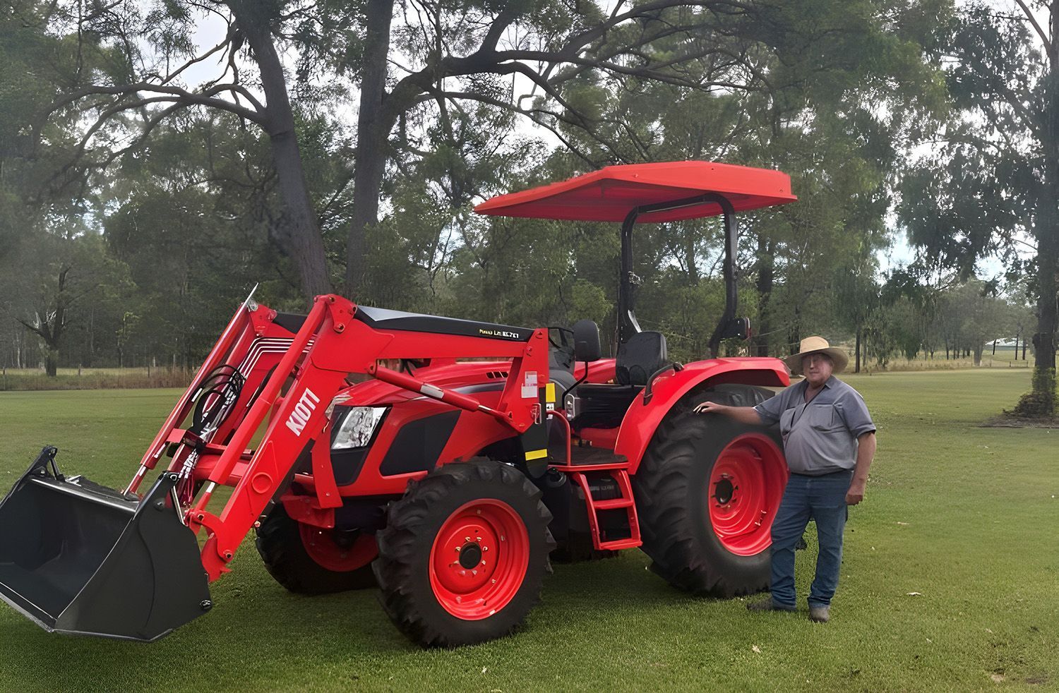 Man Standing Next To A Red Tractor With Front Loader