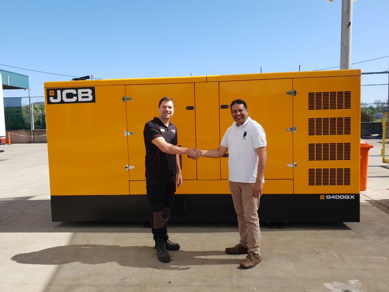 Two People Standing Next To JCB generator — North Coast Construction Equipment In Coffs Harbour, NSW