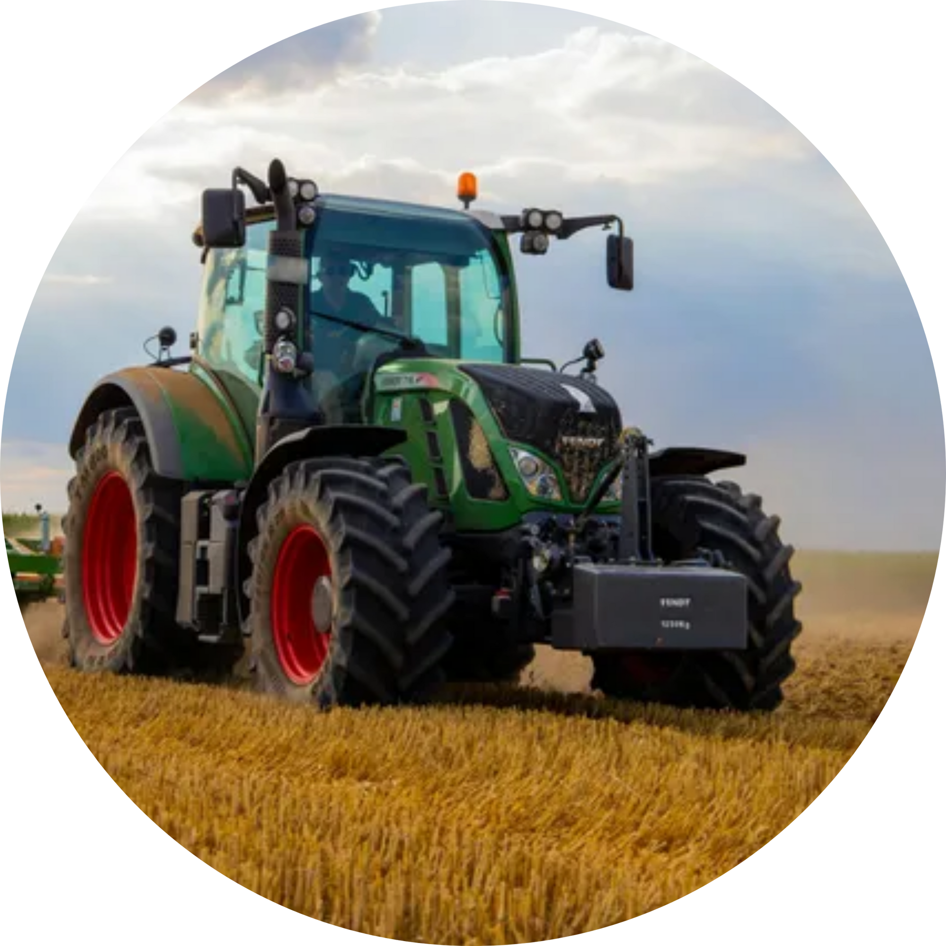 A green tractor is plowing a field of wheat.