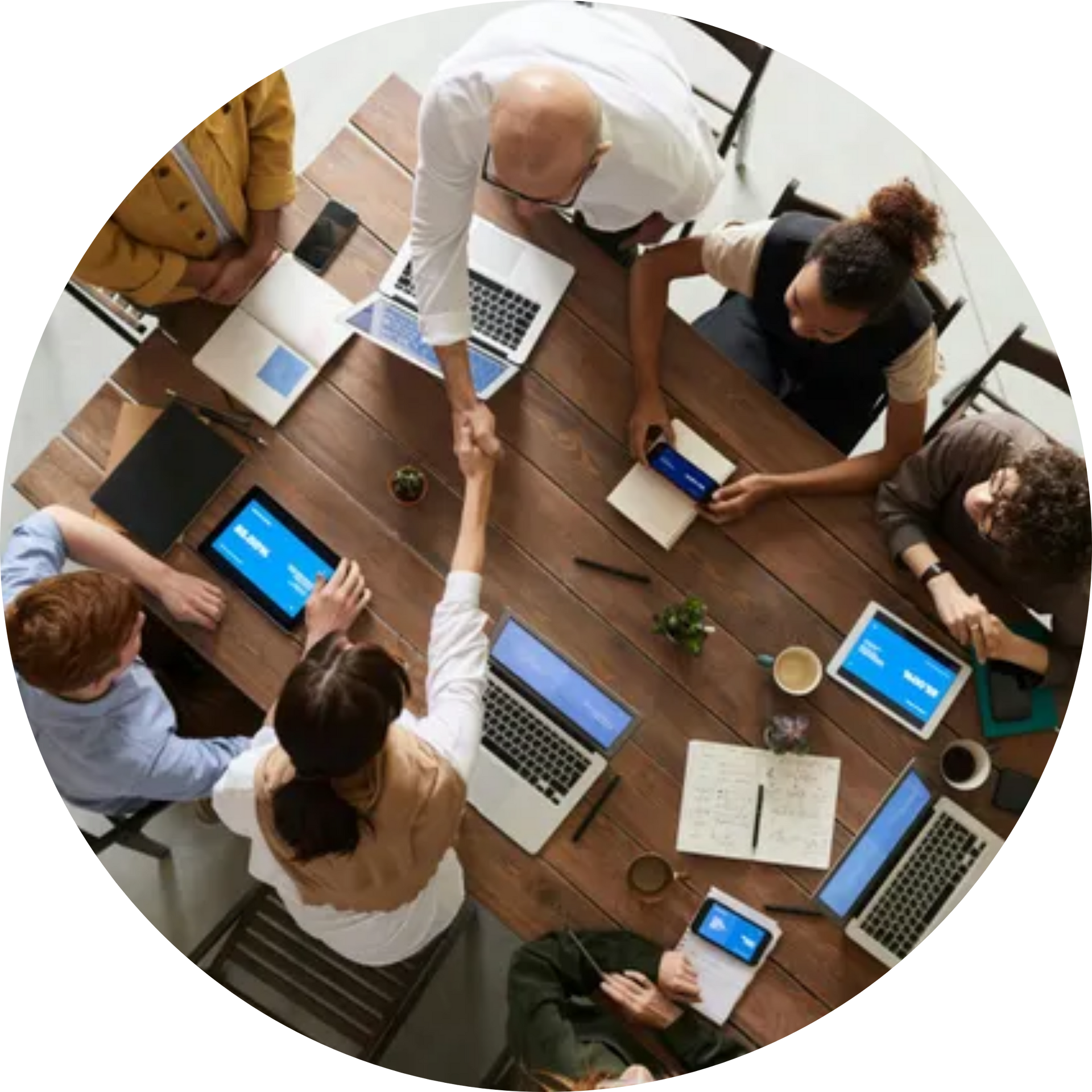 A group of people are sitting around a table shaking hands.