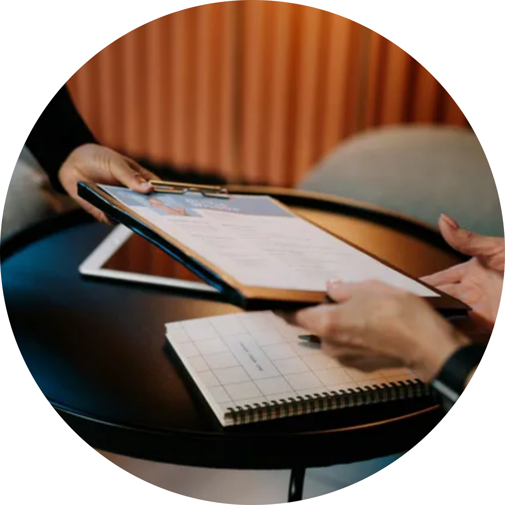 Two people are sitting at a table looking at a clipboard.