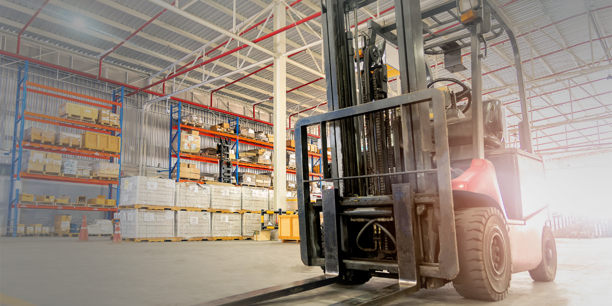 A forklift is driving through a large warehouse.