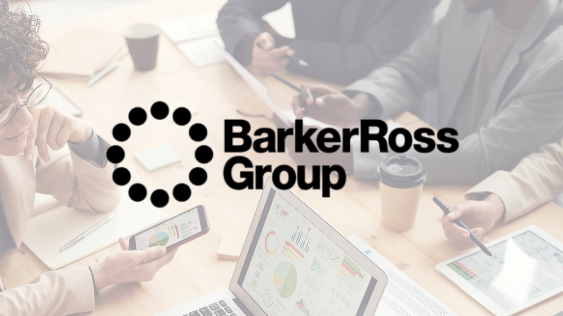 A group of people are sitting around a table with a barker ross group logo in the background.